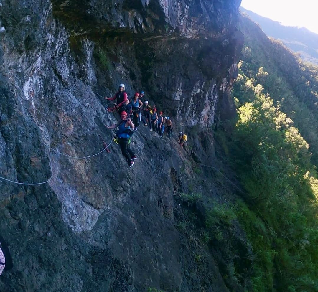 Canyoning im Aktivurlaub auf La Réunion beim REISEBÜRO Wache, Erfurt, buchen; im Bild: Menschen, die auf einem Hang eines Berges hintereinander und angeseilt klettern.