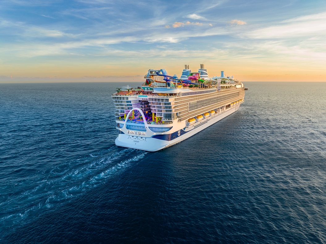 Eine Kreuzfahrt auf der Icon of the Seas buchen, ein Bucket-List-Traum, bestens beraten erfüllbar im REISEBÜRO Wache, Erfurt; im Bild: Die Icon of the Seas fährt vom Betrachter weg auf dem Meer dem Sonnenuntergang entgegen; man sieht das Heck und die vielen Decks einschließlich Rutschen- und Pooldeck oben