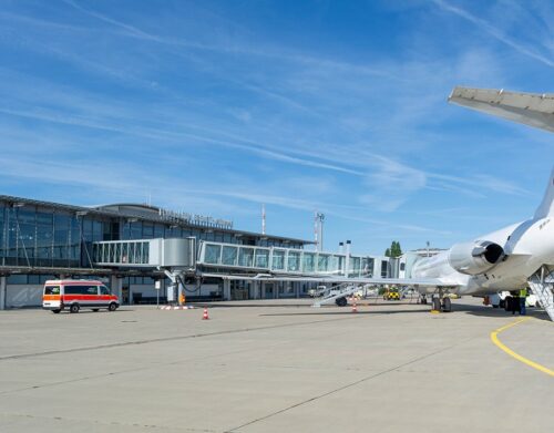 Reise buchen Erfurt beim REISEBÜRO Wache, Erfurt; im Bild: Flughafen Erfurt vom Rollfeld aus, so dass die Abfertigungshalle, ein Flugzeug am Boden und Betriebsautos zu sehen sind